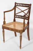 A Regency style mahogany elbow chair, with X back rest, caned seat and reeded legs,