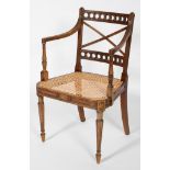 A Regency style mahogany elbow chair, with X back rest, caned seat and reeded legs,