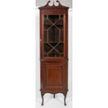 A late 19th/early 20th century mahogany display corner cabinet, pediment adorned with urn finial,