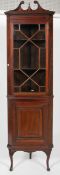 A late 19th/early 20th century mahogany display corner cabinet, pediment adorned with urn finial,