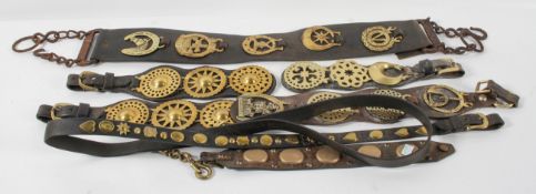 A collection of horse brasses, on leather straps,
