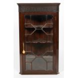 A George III mahogany corner cabinet, with blind fret carved frieze,