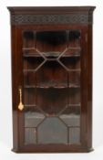 A George III mahogany corner cabinet, with blind fret carved frieze,