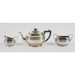 A silver three piece tea service, of oval ribbed and fluted form, the teapot with domed cover,