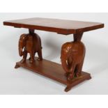 A hardwood elephant table, the shaped rectangular top on a pair of African elephant supports,