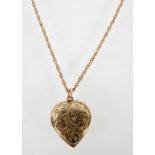 A yellow metal engraved heart shaped locket suspended on a rope link chain.