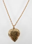 A yellow metal engraved heart shaped locket suspended on a rope link chain.