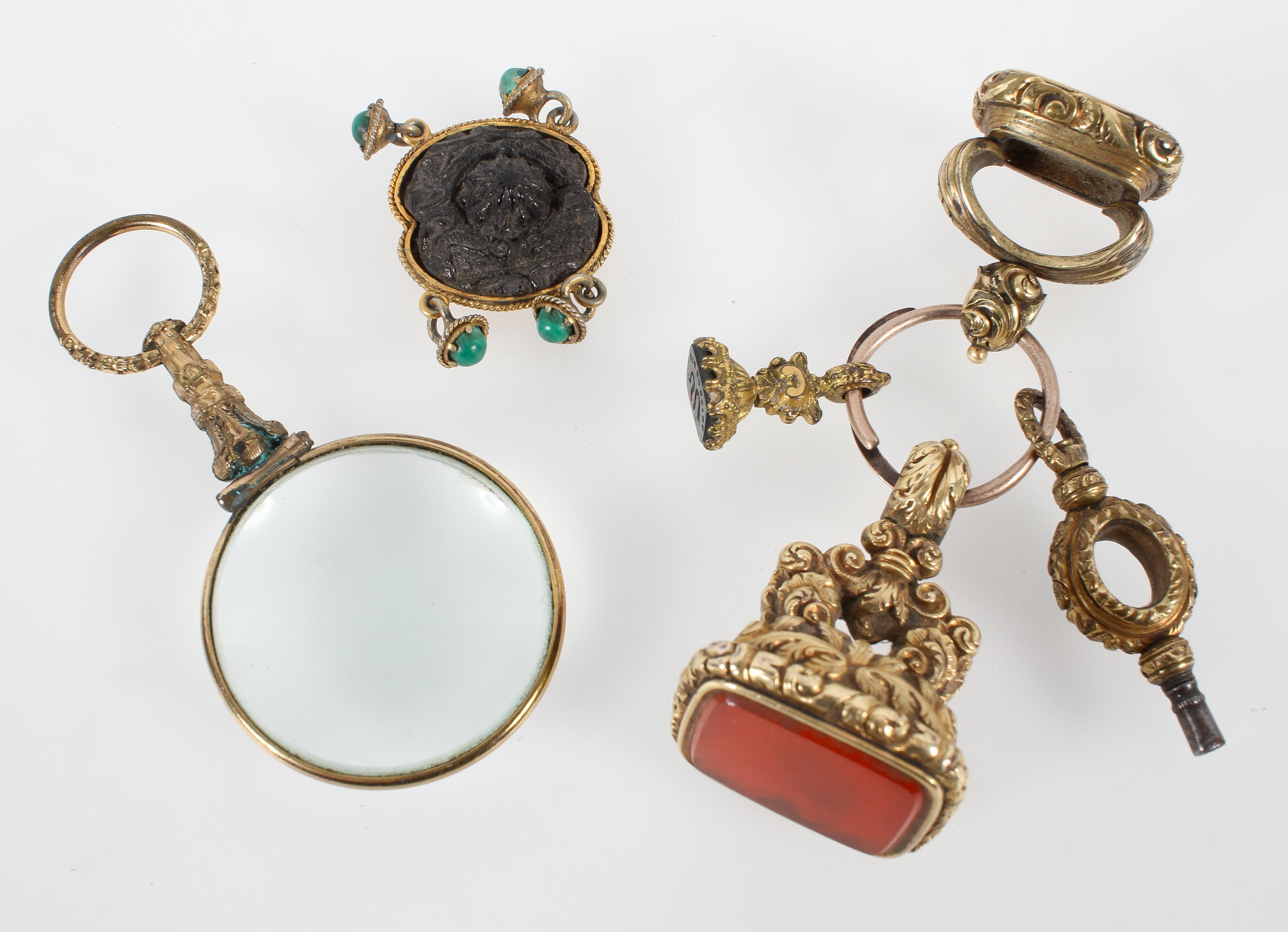 A collection of three seal fobs together with a watch key, and abstract link and a magnifying glass.
