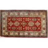 A Caucasian style rug, with geometric motifs on an abrashed red ground inside a star border,