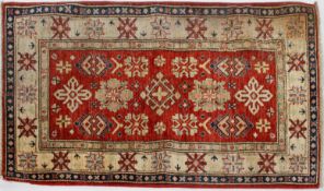 A Caucasian style rug, with geometric motifs on an abrashed red ground inside a star border,