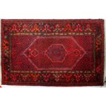A 20th century Hamadan wool dark red ground carpet, with central hexagonal panel,