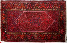 A 20th century Hamadan wool dark red ground carpet, with central hexagonal panel,