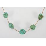 A yellow metal trace link necklace having five interspaced turquoise boulders to the centrepiece.