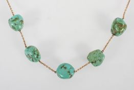 A yellow metal trace link necklace having five interspaced turquoise boulders to the centrepiece.