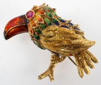 A yellow metal brooch in the style of a bird with enamelled finish and ruby set eye.