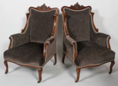 A pair of Edwardian walnut armchairs, with carved foliate crest,