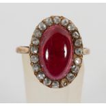 A yellow metal cluster ring principally set with a cabochon cut garnet and surrounded by rose cut