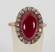 A yellow metal cluster ring principally set with a cabochon cut garnet and surrounded by rose cut