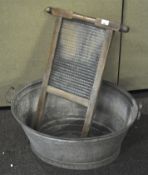 A galvanised metal hip bath style tub and a wood and glass washboard,