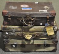 Three vintage canvas and leather bound suitcases, and a faux leather suitcase,