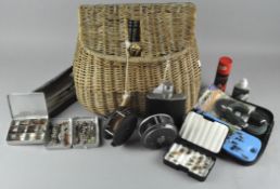 A wicker fishing creel, together with two reels, fly boxes and assorted fly fishing equipment