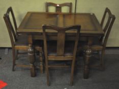 A stained oak draw leaf table with four matching chairs,