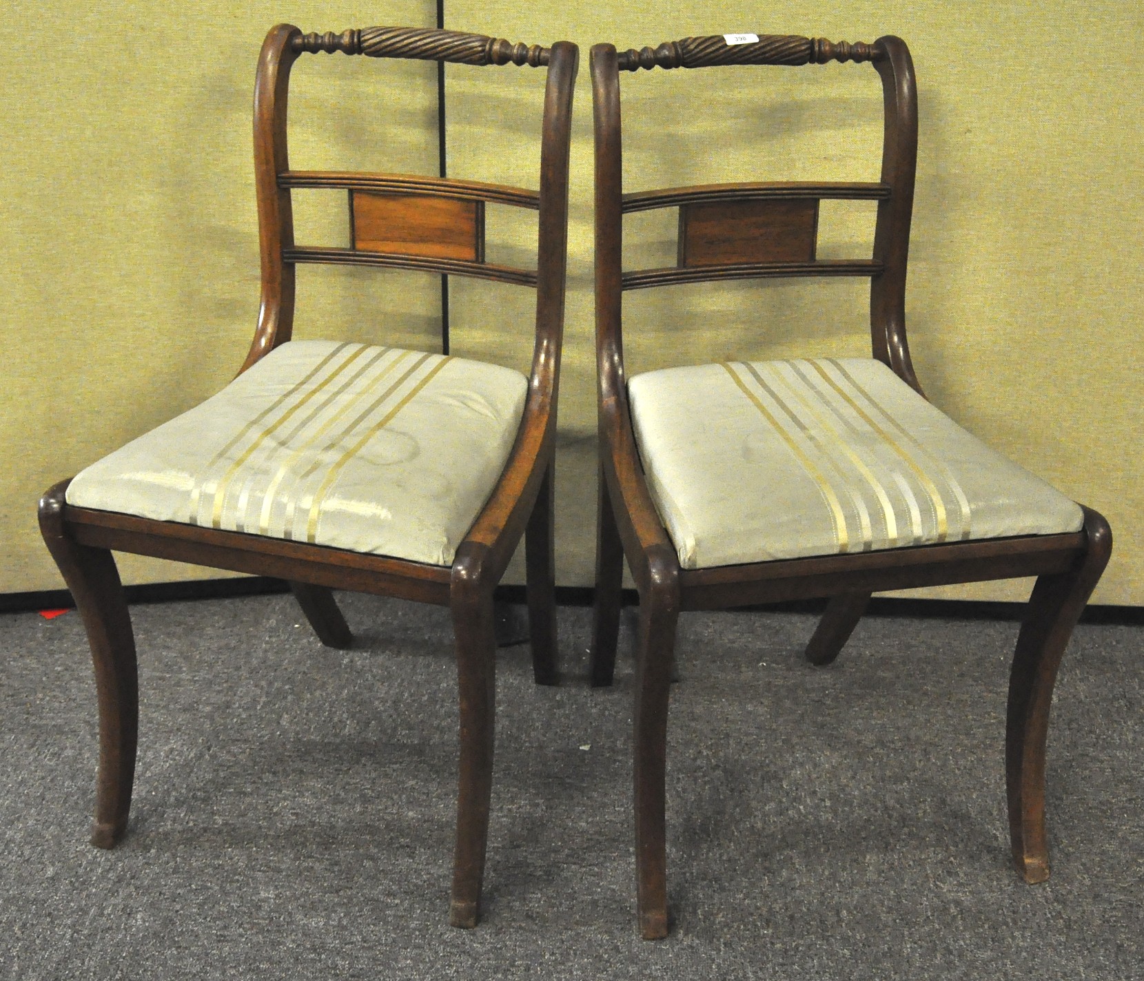 Two mahogany Regency style sabre leg dining chairs with tip in seats and rope twist back rails,