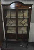 A mahogany display cabinet with glazed front and side panels, decorated with inlaid floral motifs,