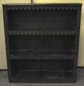 An ebonised stained wood bookcase, three tier, the front with engraved detailing,