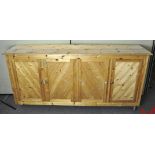 A large four door pine cabinet, raised upon castors,