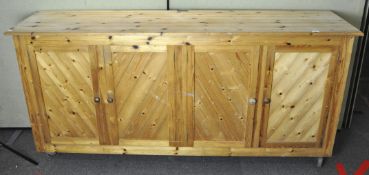 A large four door pine cabinet, raised upon castors,