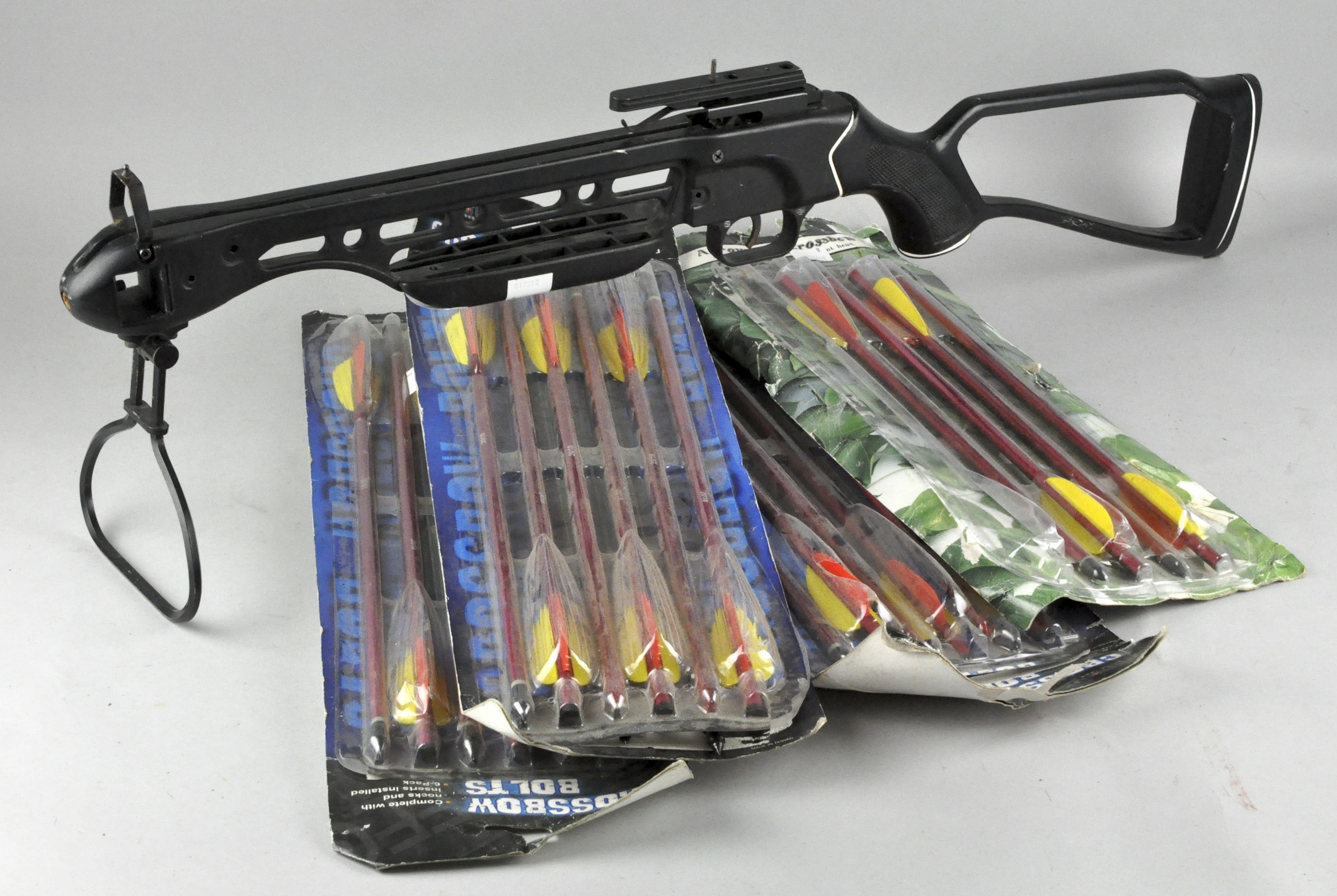 A crossbow with several packets of crossbow bolts