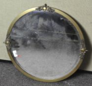 A brass framed wall mirror of circular form adorned with three urn motifs,