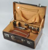 A Leather travelling vanity case fitted with lidded glass bottles and brushes etc