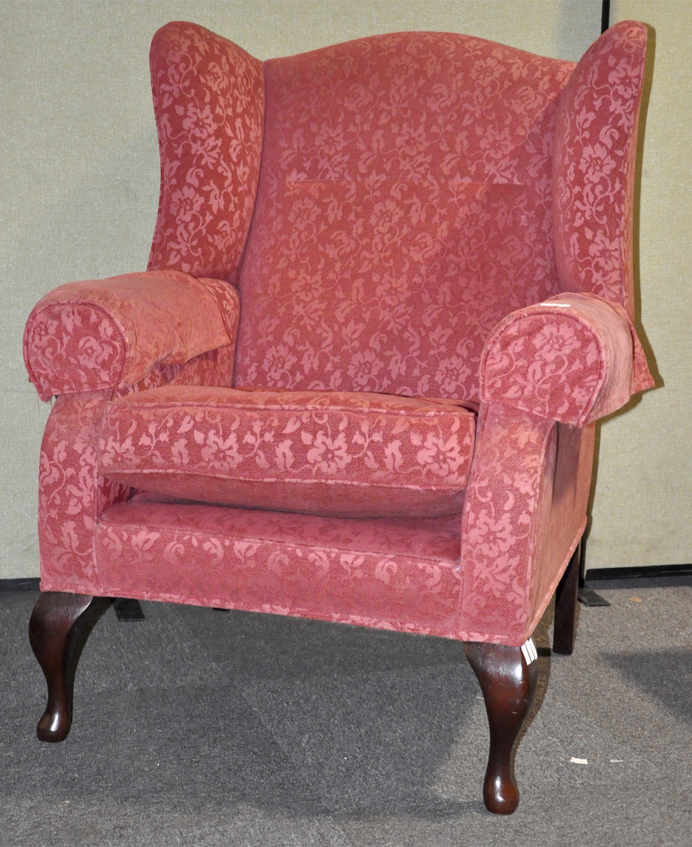 A large 18th century style wing armchair with scroll arms, raised on mahogany cabriole legs,