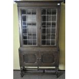 An oak display cabinet, the top half with panelled glass over a two door cupboard,