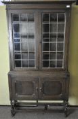 An oak display cabinet, the top half with panelled glass over a two door cupboard,