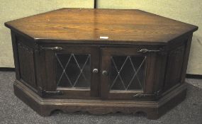 An oak TV unit with two panelled glass doors to front,