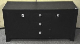 A black painted sideboard, with three central drawers with squared mirrored handles,