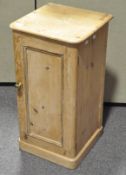 A stripped pine bedside cupboard with panelled door and single shelf,