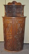 An oak corner unit with carved decoration throughout,