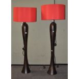 A pair of modern standard lamps, of flowing form with large red shades,