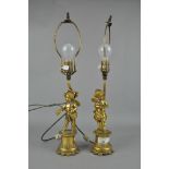 A pair of ornate gilt metal lamps depicting cherubs,