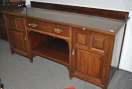 An Edwardian mahogany sideboard with two panel door cupboards flanking a drawer