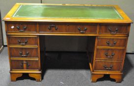 A yew wood twin pedestal desk with an arrangement of nine drawers,