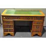 A yew wood twin pedestal desk with an arrangement of nine drawers,