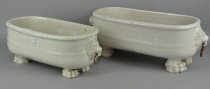 A pair of ceramic planters of oval form, twin handled, raised upon four lion paw feet,