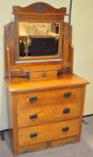 A 20th century oak dressing table with swing mirror to top, three long drawers to base,