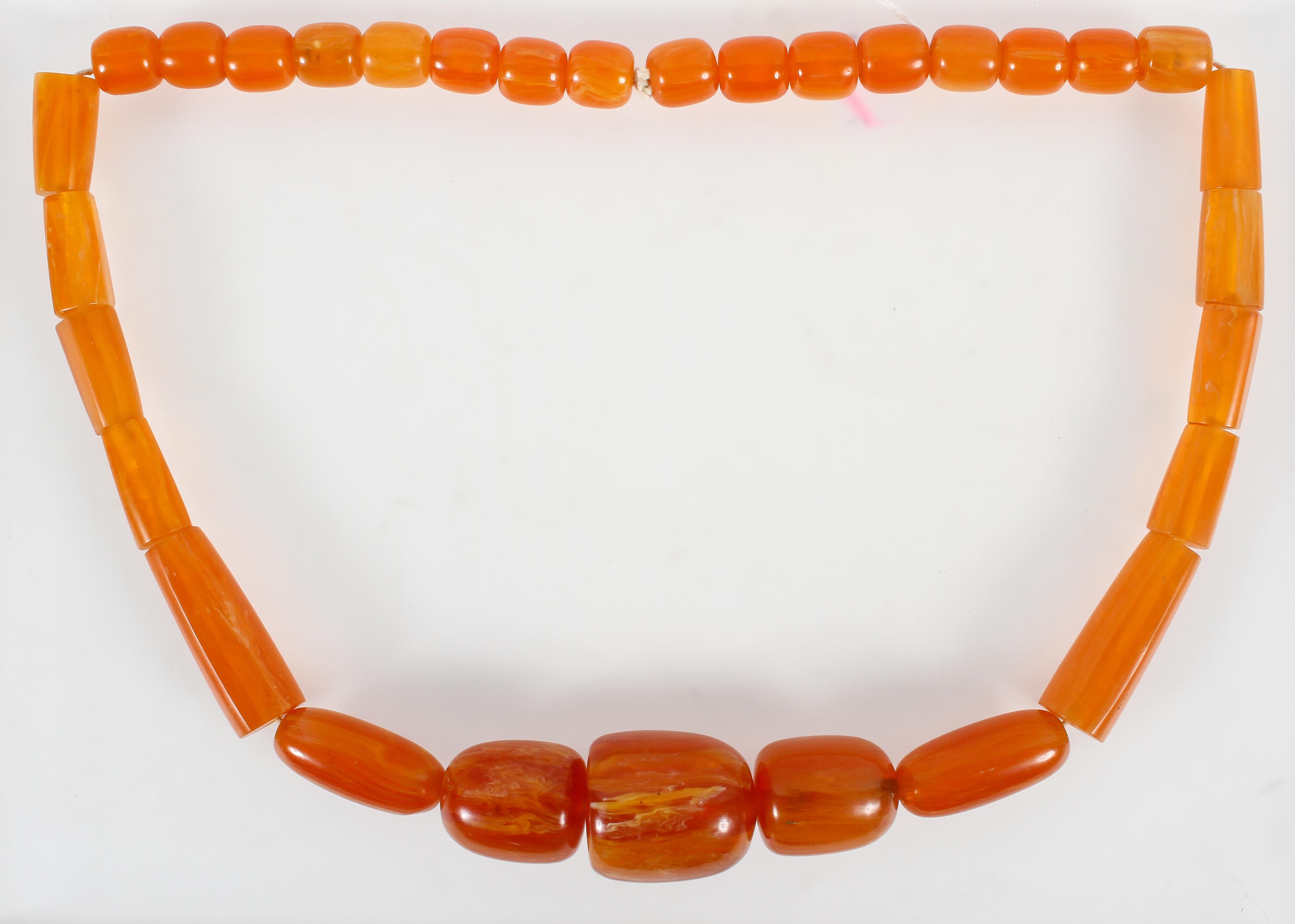 A large graduated orange bead necklace, strung plain with no clasp.