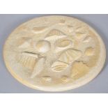 A carved and part polished stone roundel, incised PM89 to base,
